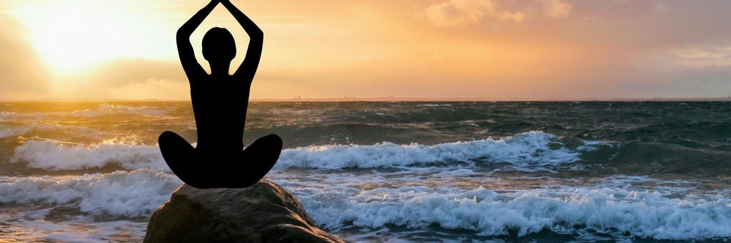 ocean scene with person on a rock, doing a yoga pose